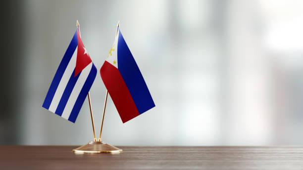 istock Cuban And Philippines Flag Pair On A Desk Over Defocused Background 951659272