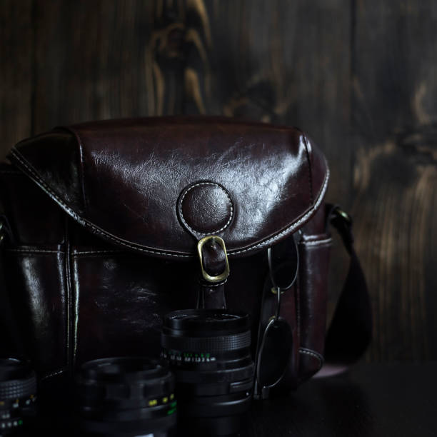 istock Vintage lens collection and camera bag on wooden table 951671756