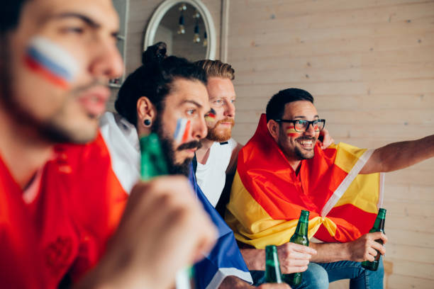 istock Friends with face paint and flags watching soccer on TV 951673268