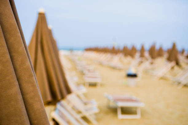 View of Beach with umbrellas and sunbeds,travel concept, getaway, holiday destination  photo with flare added to mimic a orange sunset,selective focus with creamy bokeh