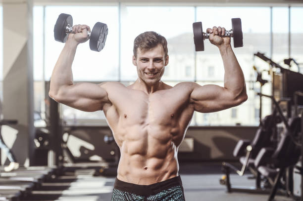 istock handsome strong bodybuilder athletic men pumping up muscles with dumbbells 951675660