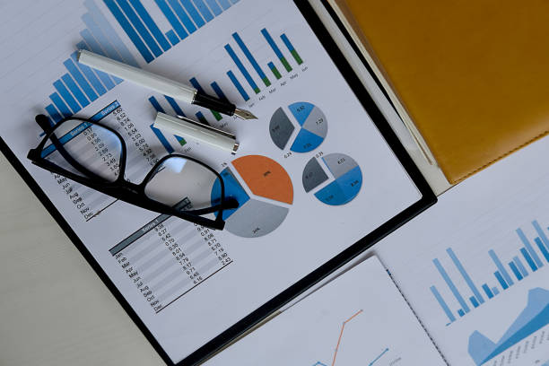 istock Business concept with copy space. Office desk table with glasses focus and analysis chart computer notebook cup of coffee on desk.Vintage tone Retro filter effect.Selective focus. 951675736