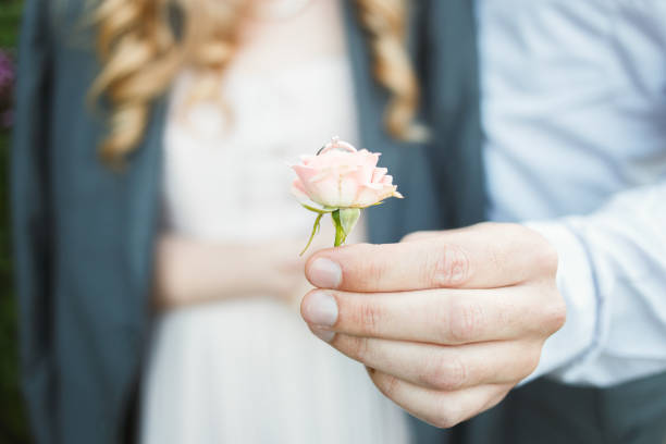 Newly wed couple's hands with wedding rings and flowers
