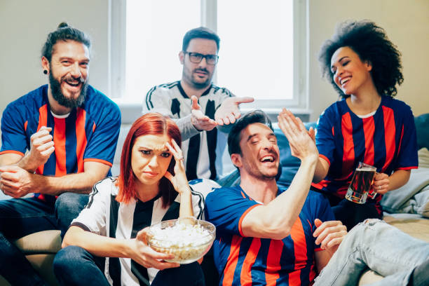 istock Friends supporting different soccer teams watching a game on TV 951676250