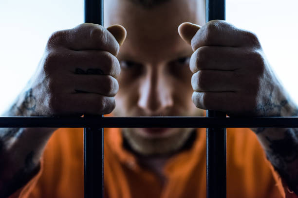 istock angry prisoner holding prison bars and looking at camera 951676578