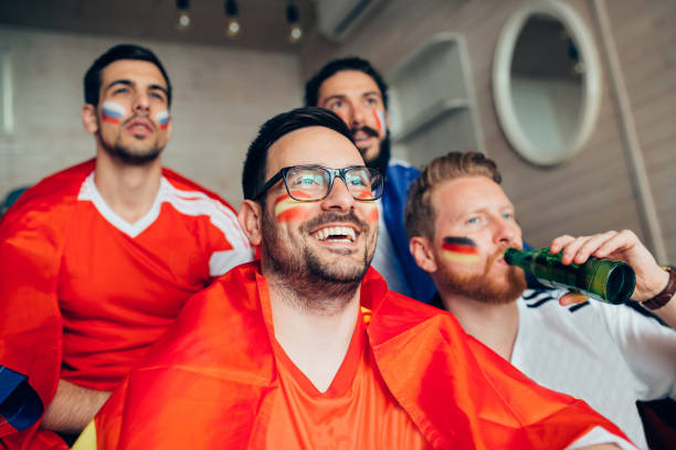 istock Man smiling and watching soccer game with friends 951677236