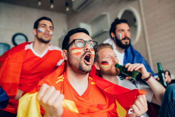 Male football supporter shouting while watching game with friends