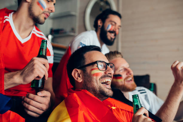 istock Man smiling while watching soccer game with friends 951677372
