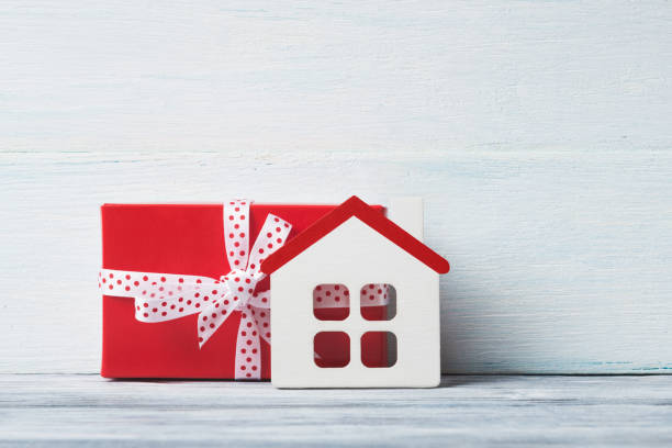 istock House model and gift box over white wooden background. 951678008