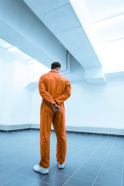 istock rear view of prisoner in orange uniform standing in prison cell 951678462