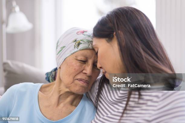 Ethnic Elderly Woman With Cancer Embracing Her Adult Daughter Stock Photo - Download Image Now