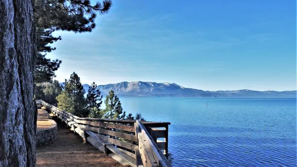 istock Path with wooden rail along a blue lake surrounded by mountains. 951679824