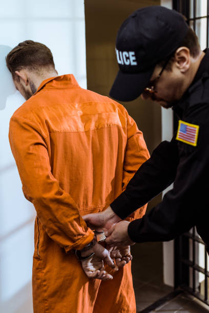 istock prison guard wearing handcuffs on prisoner 951679976