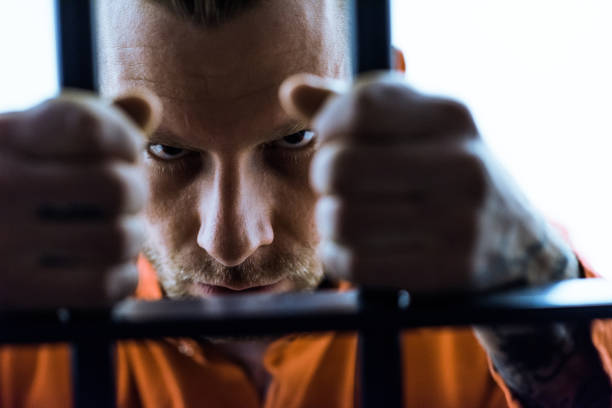 istock aggressive prisoner holding prison bars and looking at camera 951680160