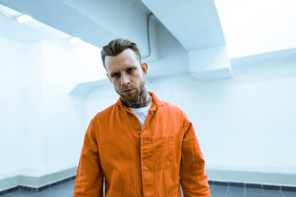 istock tattooed prisoner in orange uniform looking at camera 951680734