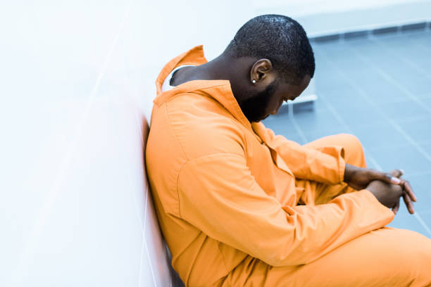 istock sad african american prisoner sitting on bench in prison cell 951680858