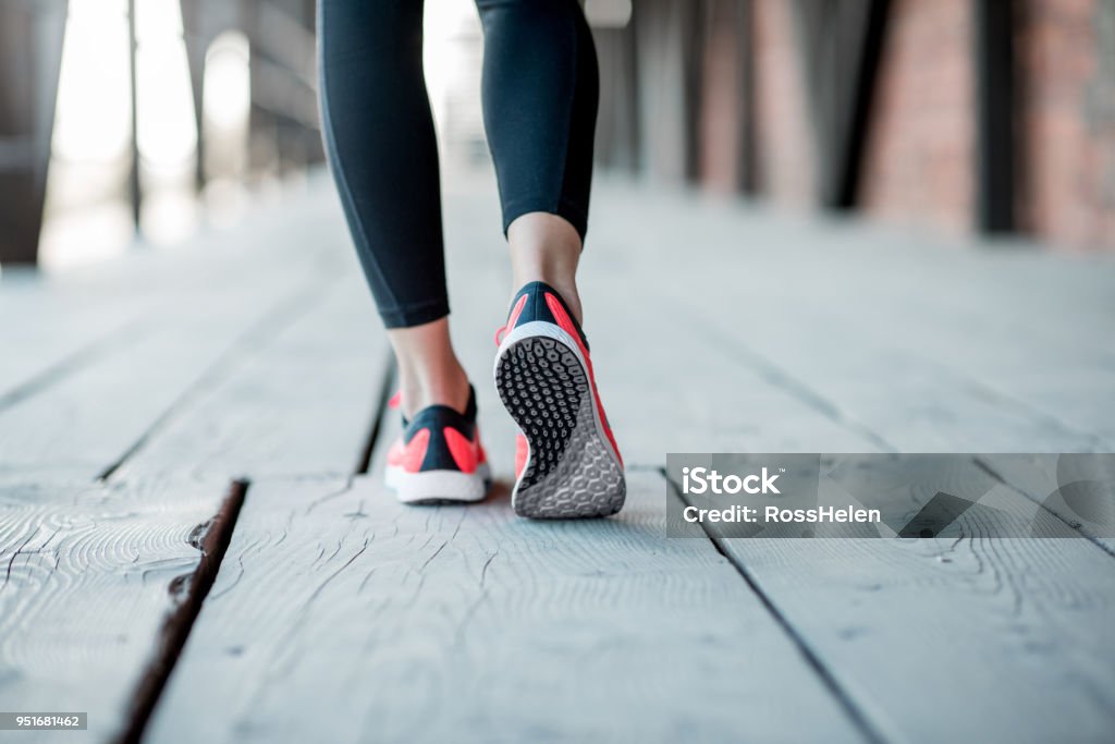 Standing in running shoes Sports woman in running shoes standing back on the wooden floor, close-up view focused on the sneakers Running Stock Photo