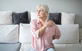 Senior lady with back pain sitting on couch