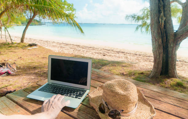 blank screen laptop on table at beach - escaping the rat race imagens e fotografias de stock