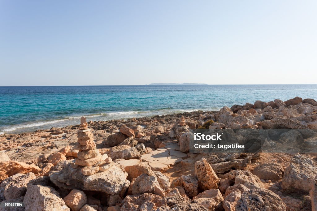 Cap de Ses Salines, Mallorca - The famous orange pebble stone at the beach of Ses Salines Cap de Ses Salines, Mallorca, Spain - The famous orange pebble stone at the beach of Ses Salines Back Lit Stock Photo