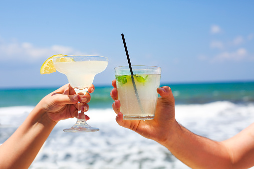 Two cocktail glasses in man and woman hands. Margarita and mojito cocktail