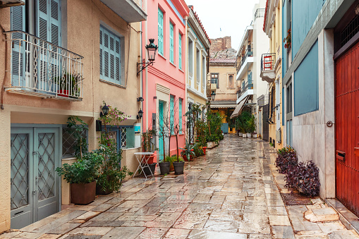 Beautiful cosy narrow street with stairs in famous Placa district in the rainy day, Old Town of Athens, Greece