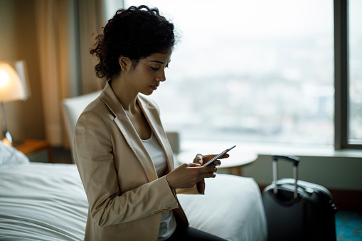 Businesswoman using mobile phone in a hotel room
