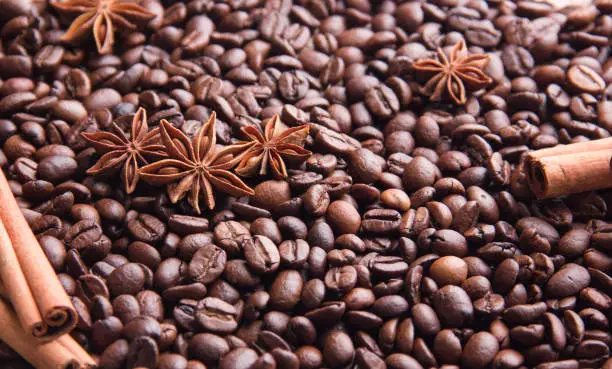 roasted coffee beans scattered on a table with cinnamon and anise