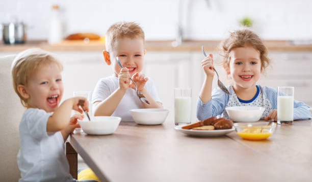 朝食を食べて幸せな面白い子供 - healthy lifestyle people eating sister ストックフォトと画像