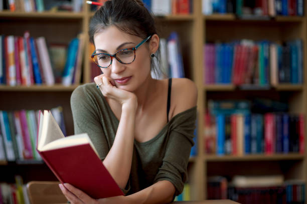 istock Young smiling woman in glasses reading a book 951741446