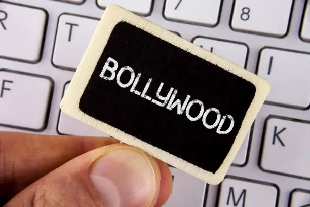 Photo of Writing note showing Bollywood. Business photo showcasing Indian cinema a source of entertainment written on Wood Piece holding by man on the Laptop.