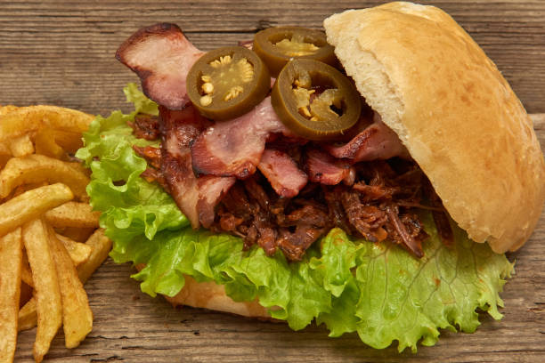 istock Barbeque Pulled beff Sandwich with green salad,crisp bacon,hot pepper jalapeno,BBQ Sauce and Fries on wooden background,Fast food 951747678