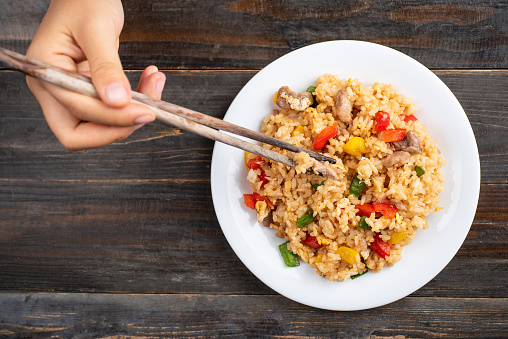 Hand holding chopsticks and eating fried rice, Asian cuisine, top view