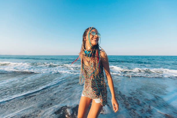 Woman with toulsed braided hair standing on beach.