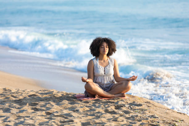istock African woman sitting on sand and meditating 951761522