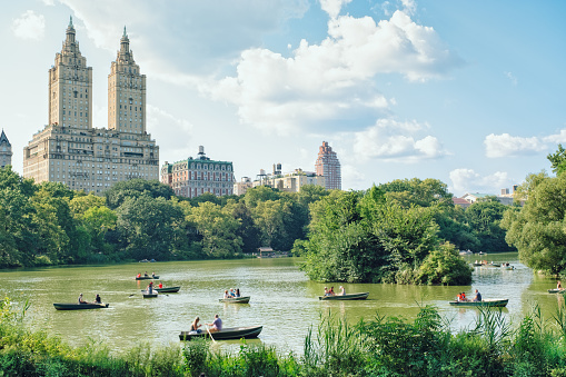 The twin towers of the Eldorado apartment building facade, the lake with people paddling and the trees of Central Park.