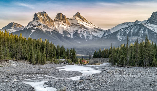 вид на гору три сестры, хорошо известную достопримечательность в кэнморе, канада - winter sunset stream snow стоковые фото и изображения