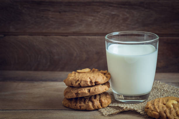 bicchiere di latte e biscotti di arachidi su sfondo legno - peanut bag nut sack foto e immagini stock