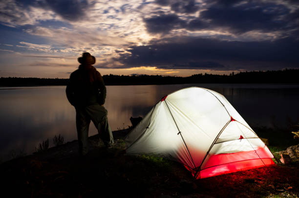 istock Illuminated Tent and Man by Lake 951808178