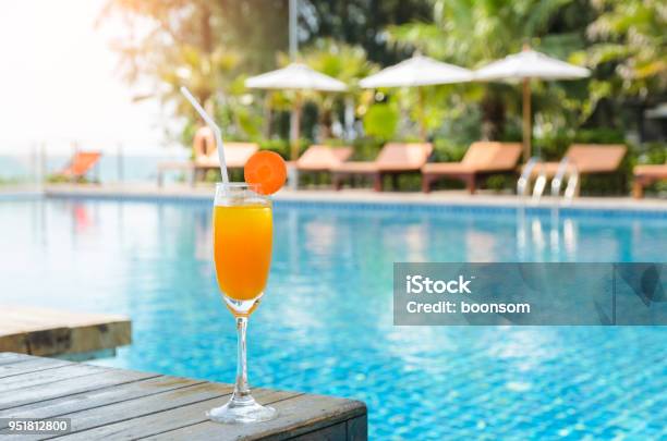 Photo libre de droit de Verre De Jus Dorange Sur Une Table En Bois Avec Fond Vue Piscine banque d'images et plus d'images libres de droit de Piscine