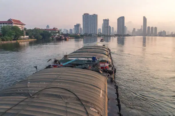 Photo of Tug boats drag barge on Chao Phraya River in the morning, a popular transportation in Thailand because of low cost.