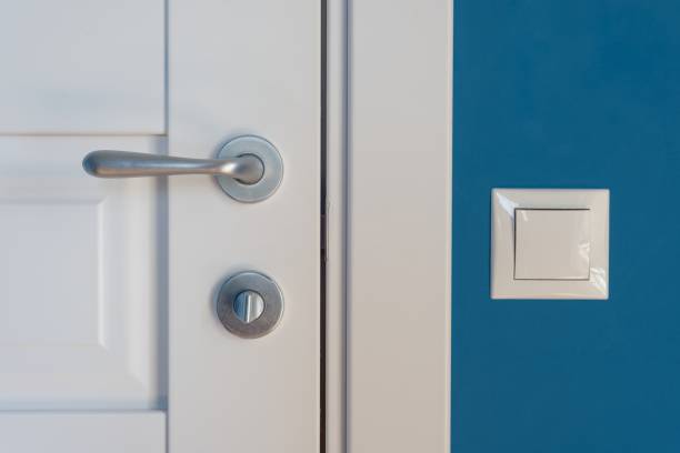 elementi ravvicinati dell'interno dell'appartamento. dettaglio di una porta interna bianca con maniglia e chiusura della porta cromata, interruttore della luce sul muro - keyhole door wood office foto e immagini stock