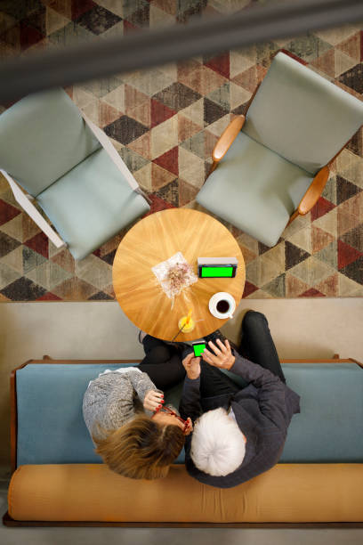 istock Senior couple sitting in retro hotel drink coffee and chatting. Active seniors, using digital tablet and smartphone, browsing the internet.  Directly above. 951831218
