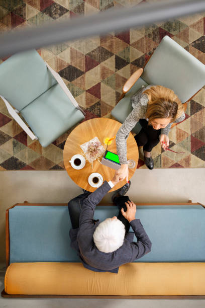 istock Senior couple sitting in retro hotel drink coffee and chatting. Active seniors, using digital tablet and smartphone, browsing the internet.  Directly above. 951831574