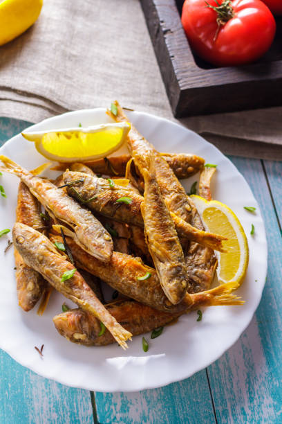 istock Fried mullet with lemon and herbs on a ceramic plate 951839660
