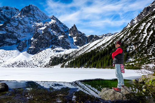 Middle-aged tourist on a trip admires views around Morskie Oko lake, Tatra Mountains, Poland