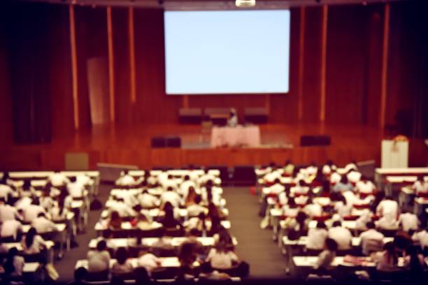 blurred image of students, audience and keynote speaker for freshman orientation day or lecture in international conference hall during graduation ceremony. event university. vintage film color. - winners podium audio imagens e fotografias de stock