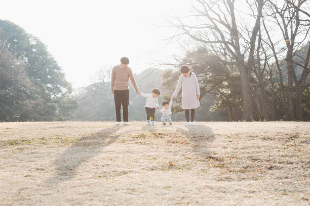 Portrait of family holding each other's hands together Japanese family standing on small hill in the park. japanese ethnicity photos stock pictures, royalty-free photos & images