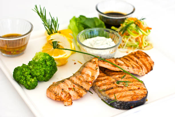 steaks of salmon, grilled. served with vegetables and spices on the white plate - main course salmon meal course imagens e fotografias de stock