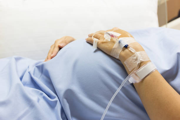 Asian Pregnant Woman patient is on drip receiving a saline solution on bed VIP room at hospital. Asian Pregnant Woman patient is on drip receiving a saline solution on bed VIP room at hospital, selective focus. sick woman hospital bed stock pictures, royalty-free photos & images